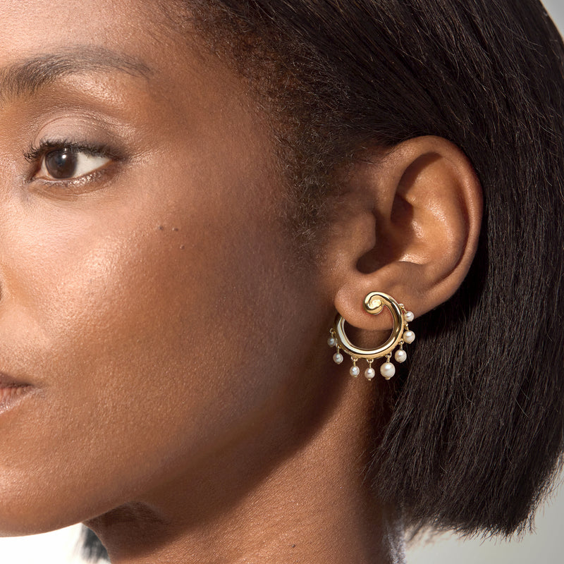 Pearl swirl clip earrings in 18kt yellow gold, white pearls around hoop, on-ear close-up
