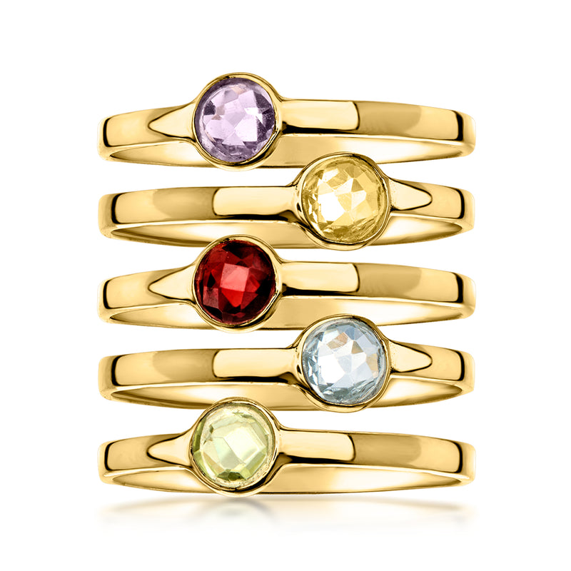 Five gold-tone stack rings with purple, yellow, red, blue, and green round gemstones