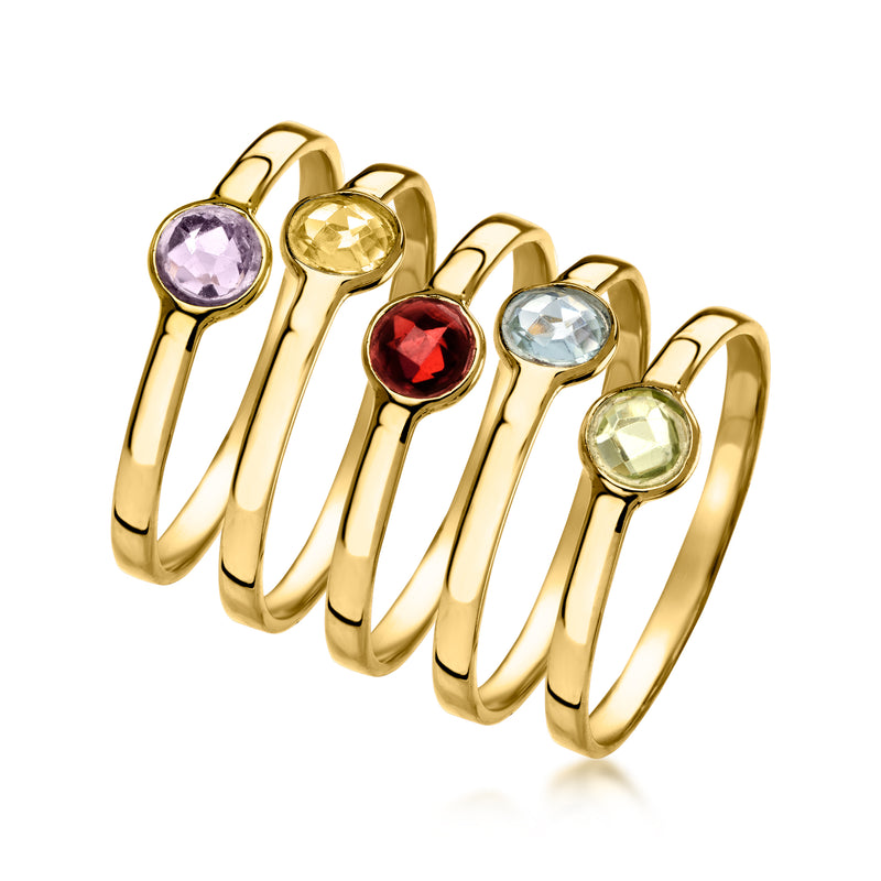 Five gold-tone stack rings lined up, featuring lavender, yellow, red, light blue, green stones