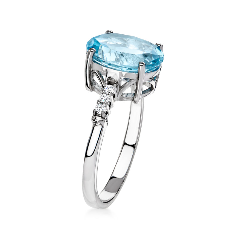 Sterling silver ring showing oval sky blue topaz in prong setting with side clear stones