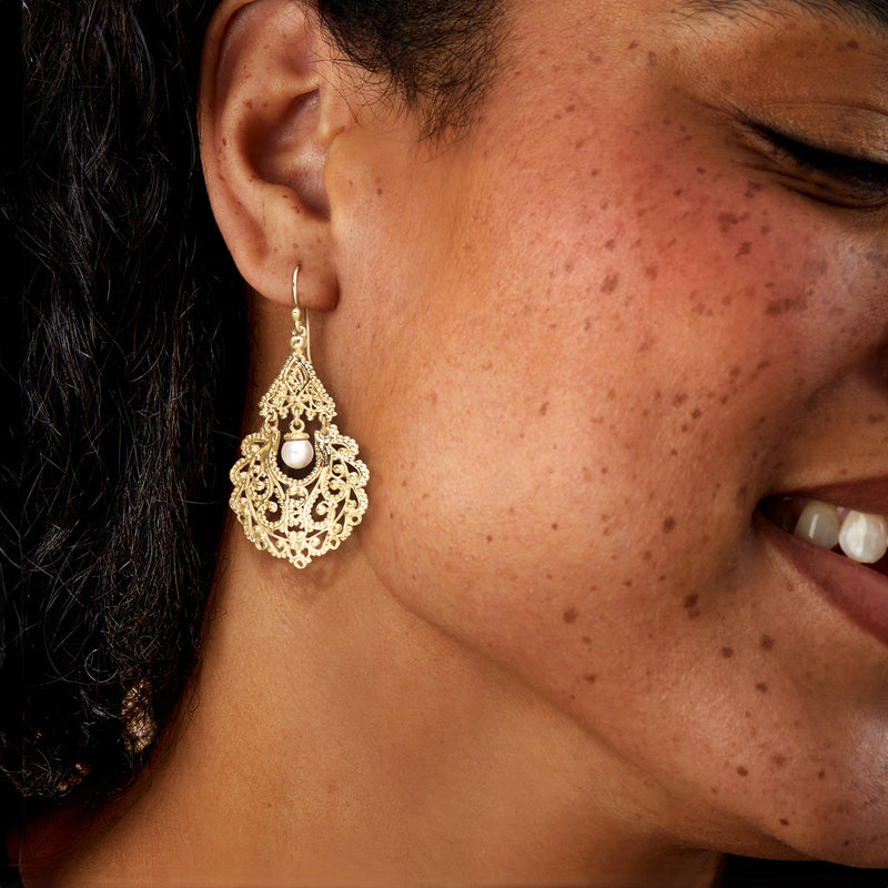 Gold-tone filigree chandelier earrings with white pearl drop on ear