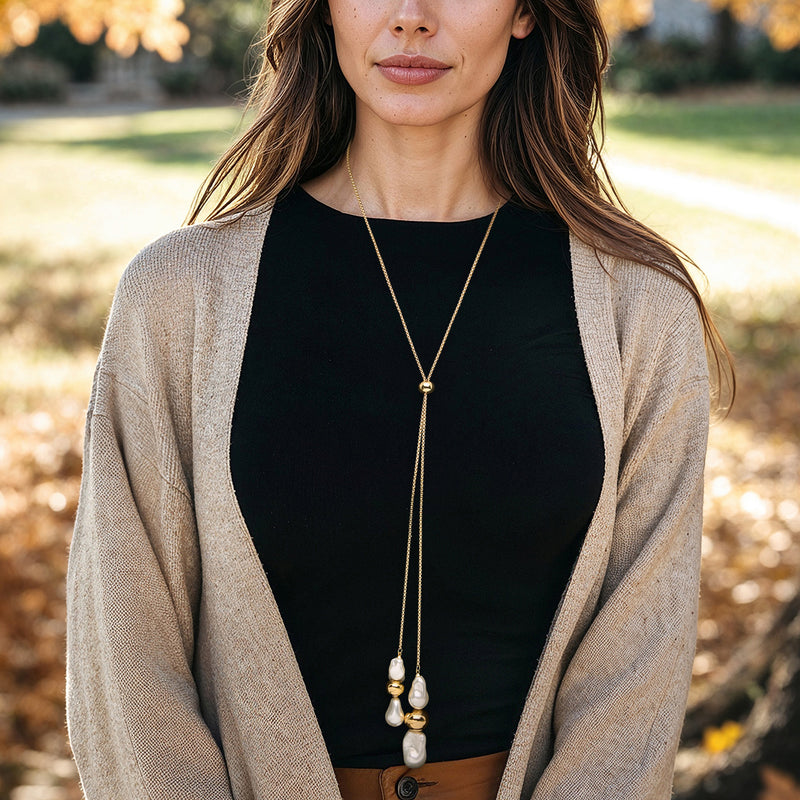 Gold-plated lariat necklace worn with long chain and white faux baroque pearl drops