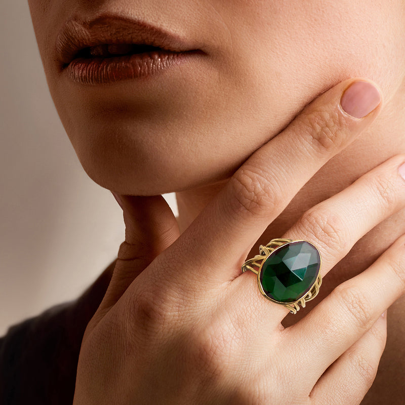 Gold-plated ring with green oval simulated emerald on finger, close-up