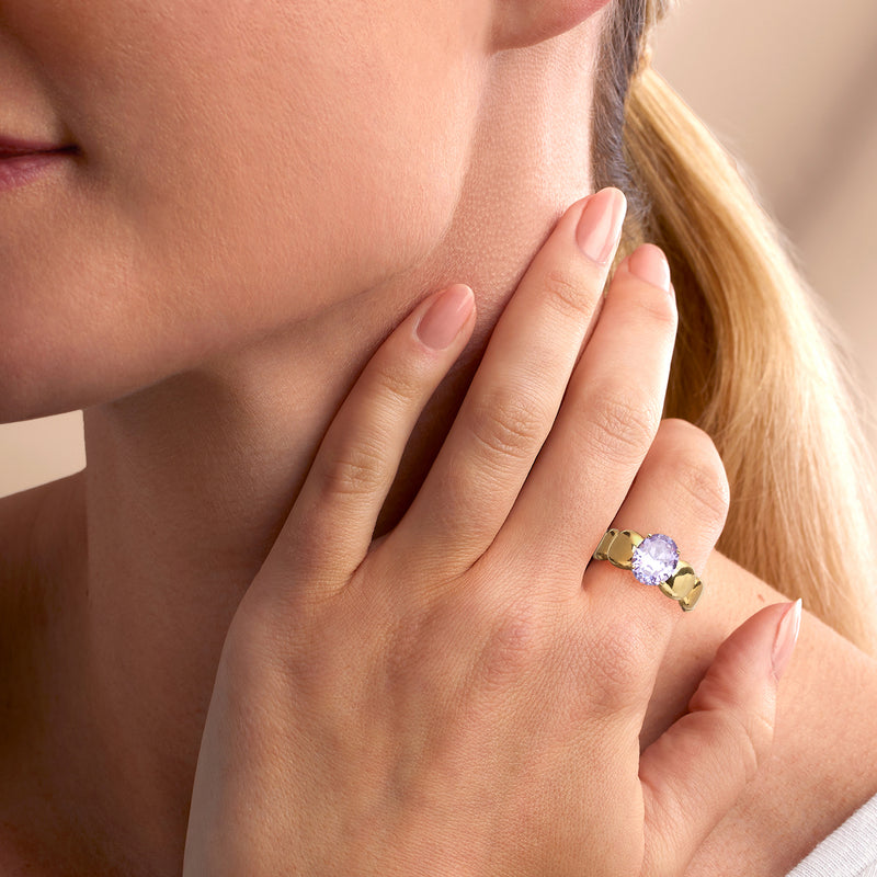 Gold-plated ring with oval simulated amethyst on hand, close-up