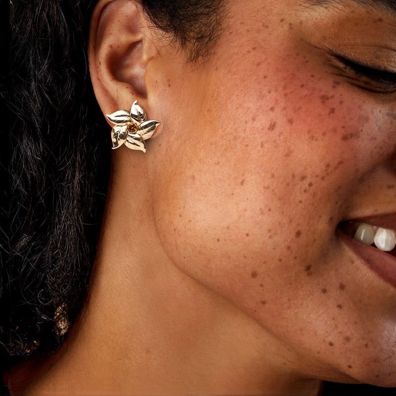 Gold flower clip earrings with citrine center worn on ear