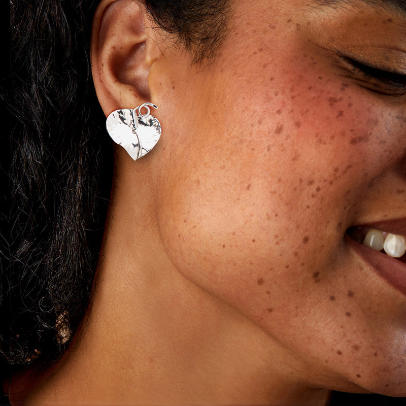 Sterling silver hammered heart leaf clip earrings on ear, close-up