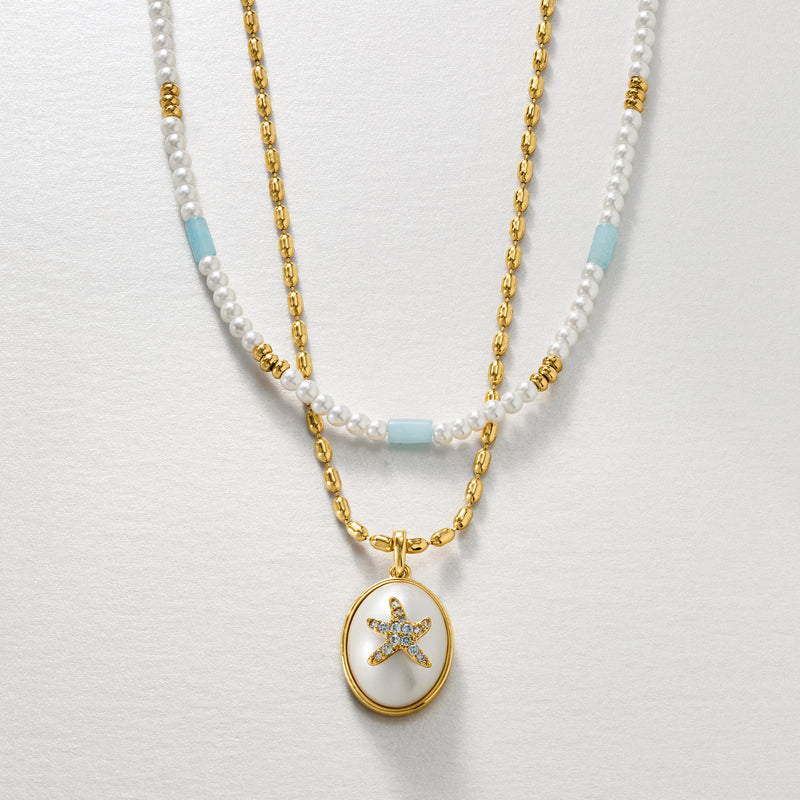 Layered necklaces with white and light blue beads, gold chain, and starfish charm pendant