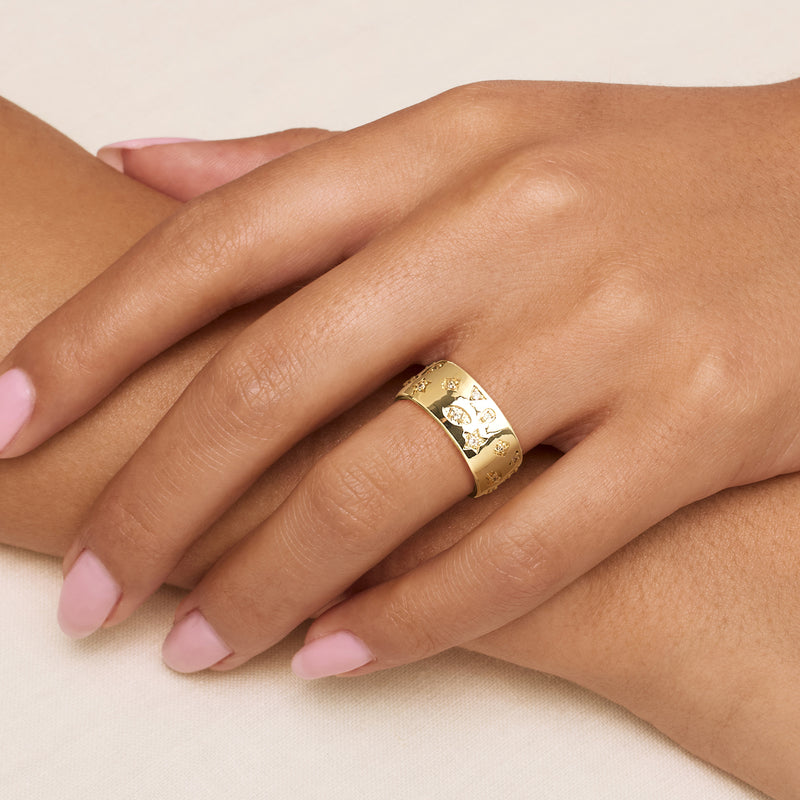 Yellow gold-plated ring on finger, wide band with mixed-shape CZ stones