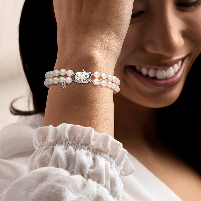Pearl bracelet on wrist with decorative clasp, tiny links, and M charm