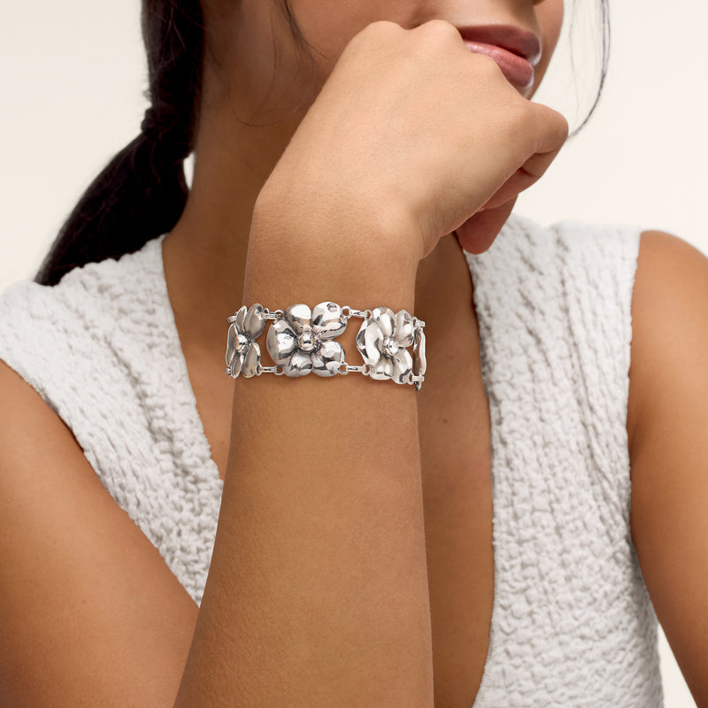 Sterling silver floral link bracelet worn on wrist, bright round flowers and toggle clasp