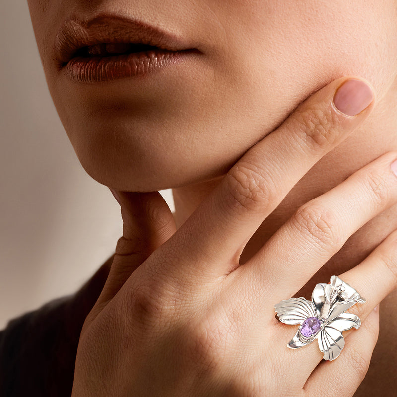 Sterling silver amethyst flower ring worn on hand with purple center gemstone