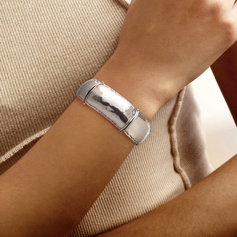Sterling silver wide link bracelet worn on wrist, polished hinged cuff-style links