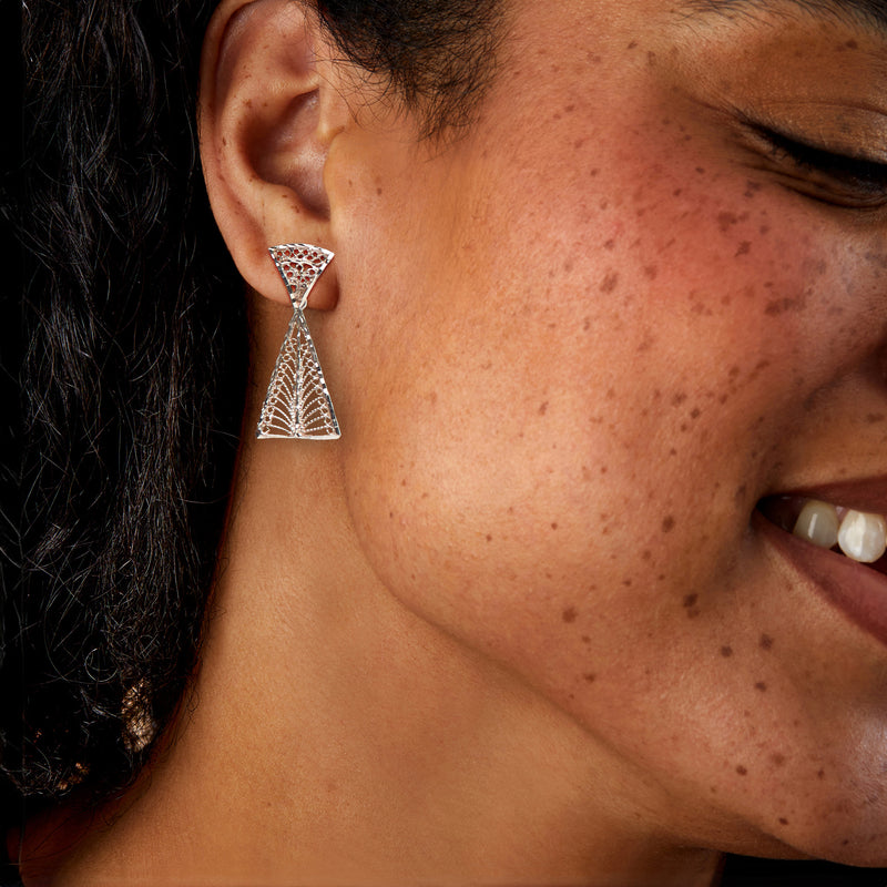 Sterling silver geometric lattice drop earrings worn on ear, triangular openwork dangles