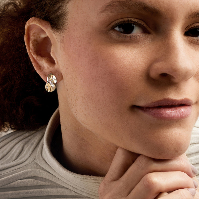 Yellow gold twist diamond clip/post earrings on ear, close-up of oval twist design