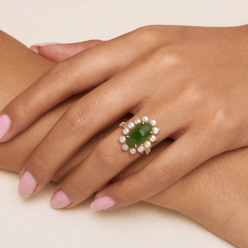 Green oval ring with white pearls on hand, yellow gold basket setting