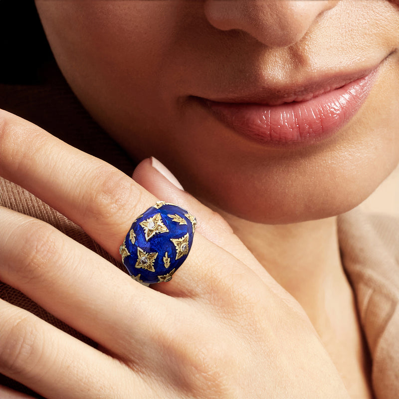 Blue enamel dome ring on finger with gold motif settings and diamond accents