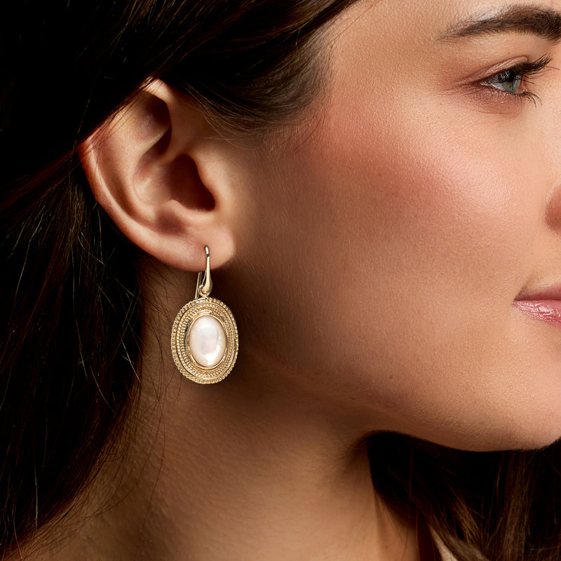 Oval mother-of-pearl drop earrings in yellow gold-tone, textured frame, earwire, side view