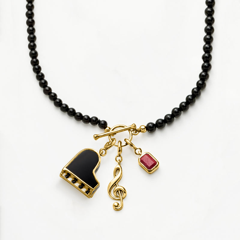 Black bead necklace with gold piano charm, enamel black keys, plus note and red charm.