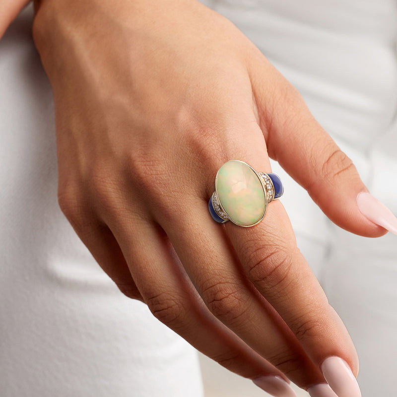 Oval opal and blue lapis ring on hand; 14kt gold with diamond set band