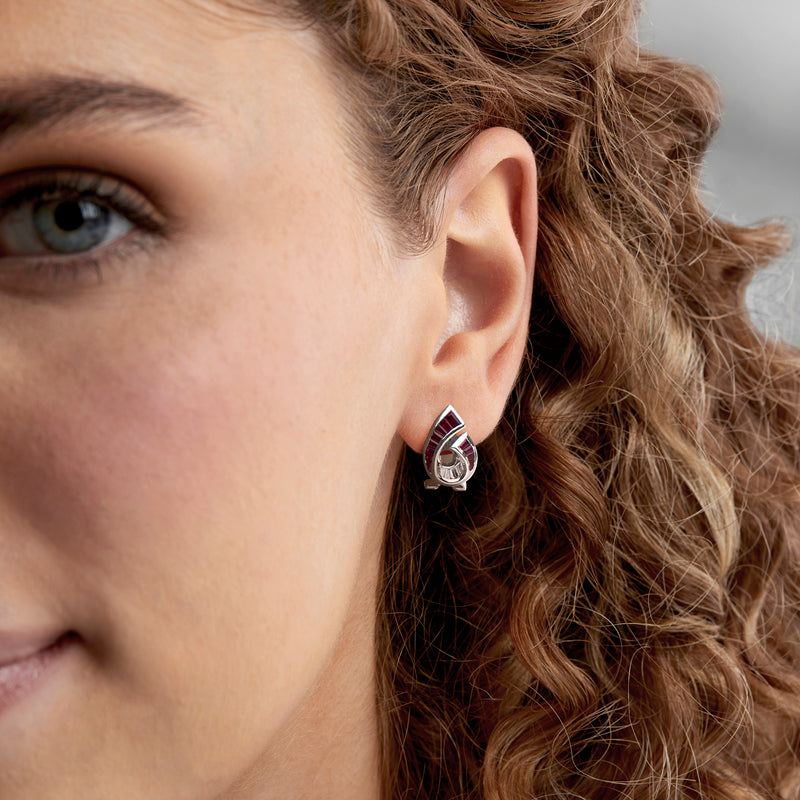 Ruby and diamond swirl teardrop earrings on model ear, 18kt white gold