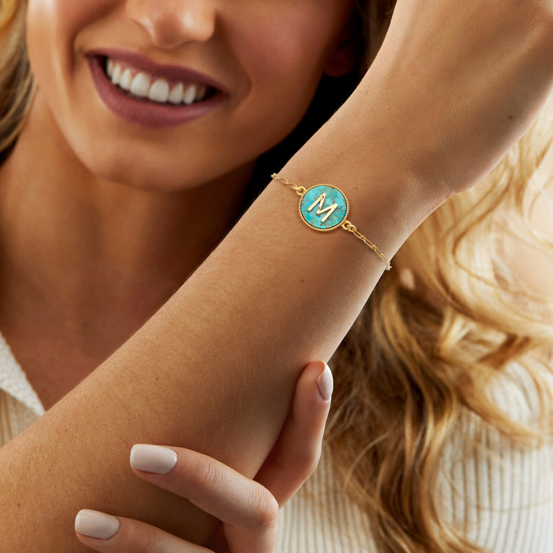Gold turquoise initial bracelet worn on wrist with letter M medallion