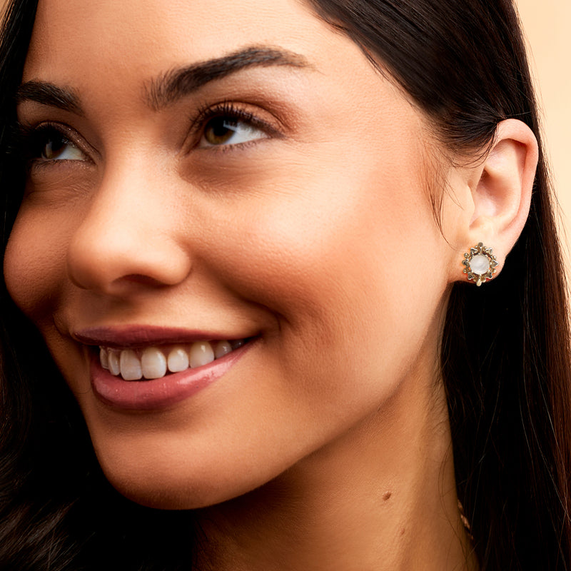 Moonstone gold stud earrings on model ear, round white cabochon with textured rim