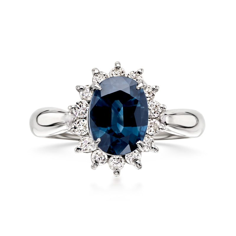 Platinum ring with dark blue oval sapphire center and diamond halo setting