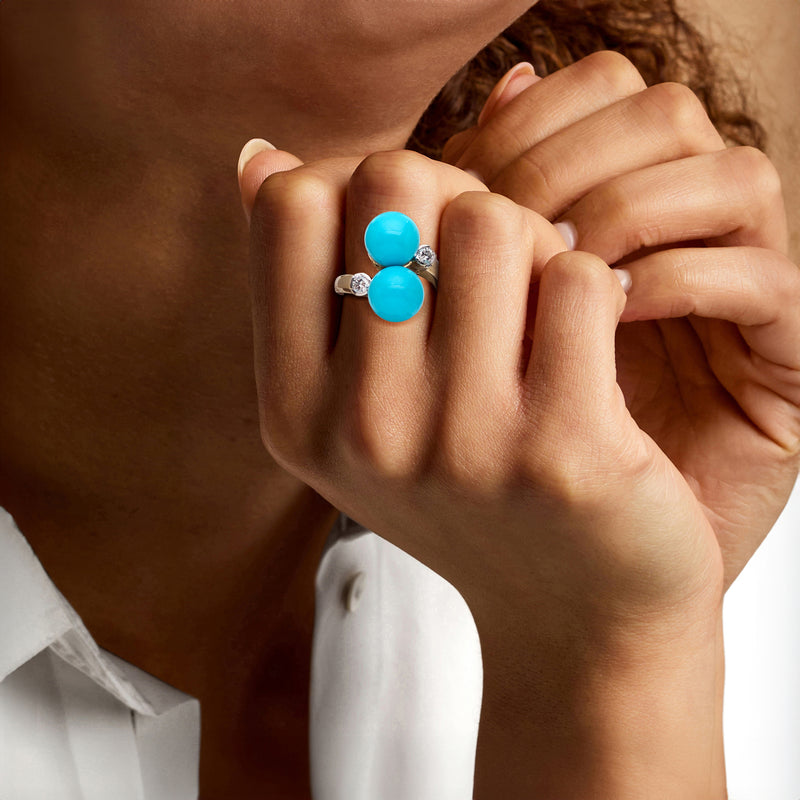Yellow gold ring with two blue turquoise cabochons and small diamond accents on hand