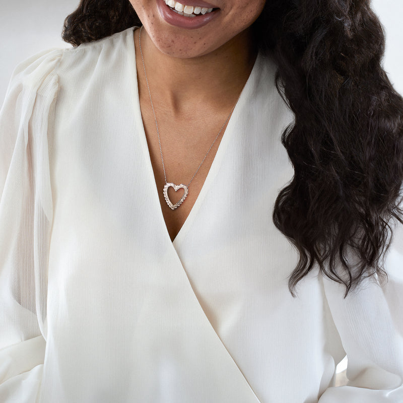 Diamond heart necklace worn on a white blouse, pendant centered on a fine chain
