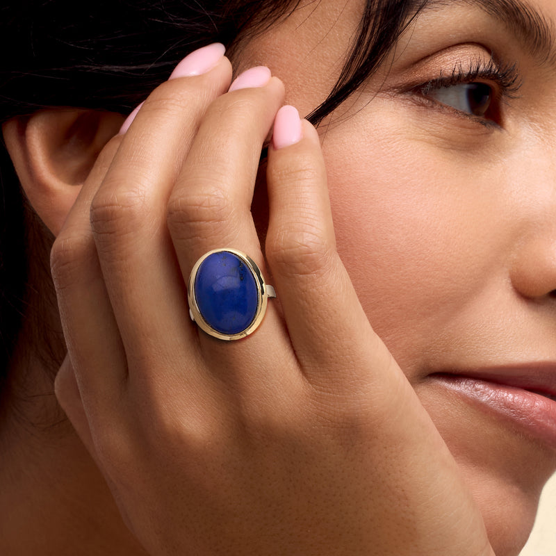 Lapis oval cabochon ring in 14kt yellow gold on finger, blue stone close-up