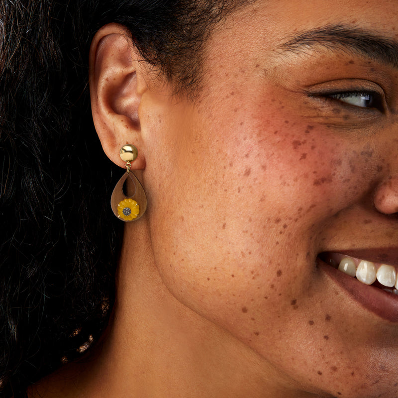 Sunflower drop earrings worn on ear, teardrop wood with yellow flower and gold hardware