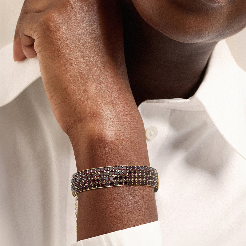 Garnet bangle bracelet on wrist, gold-toned bezel with red gemstone rows