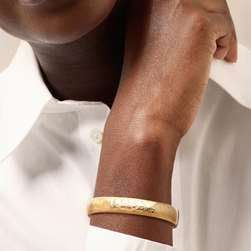 Gold-filled floral bangle bracelet worn on wrist, polished engraved pattern