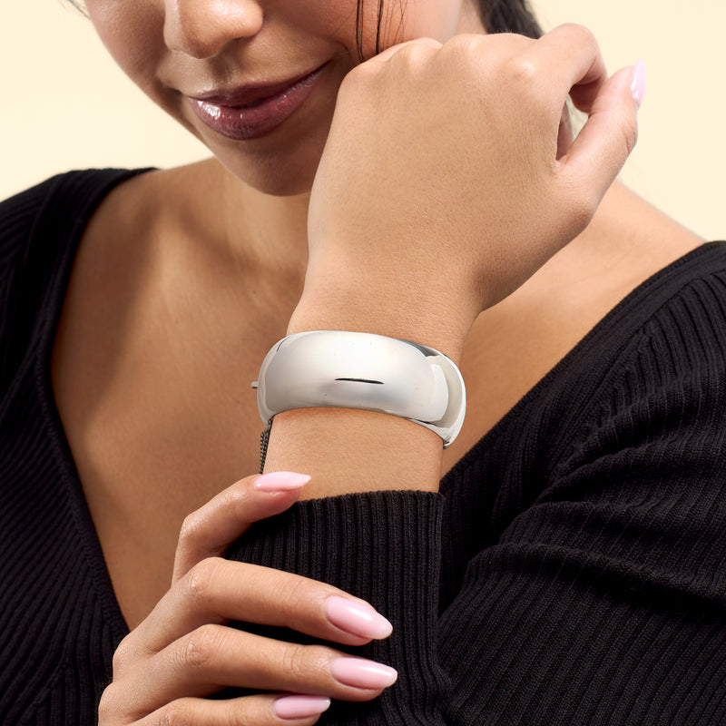 Wide sterling silver bangle on wrist, smooth polished curved design