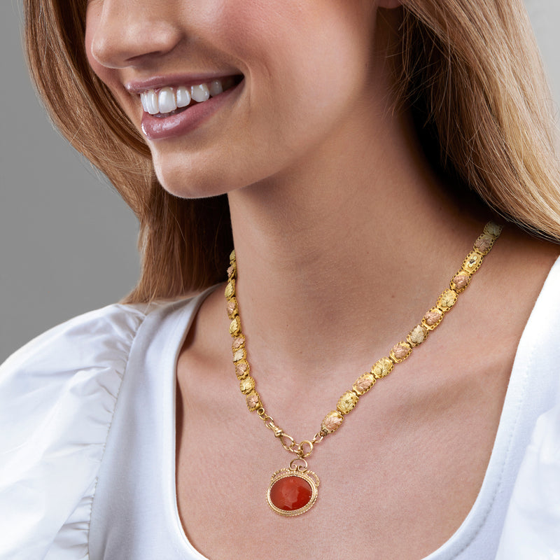 Gold-filled carnelian necklace on model, oval red pendant with textured link chain