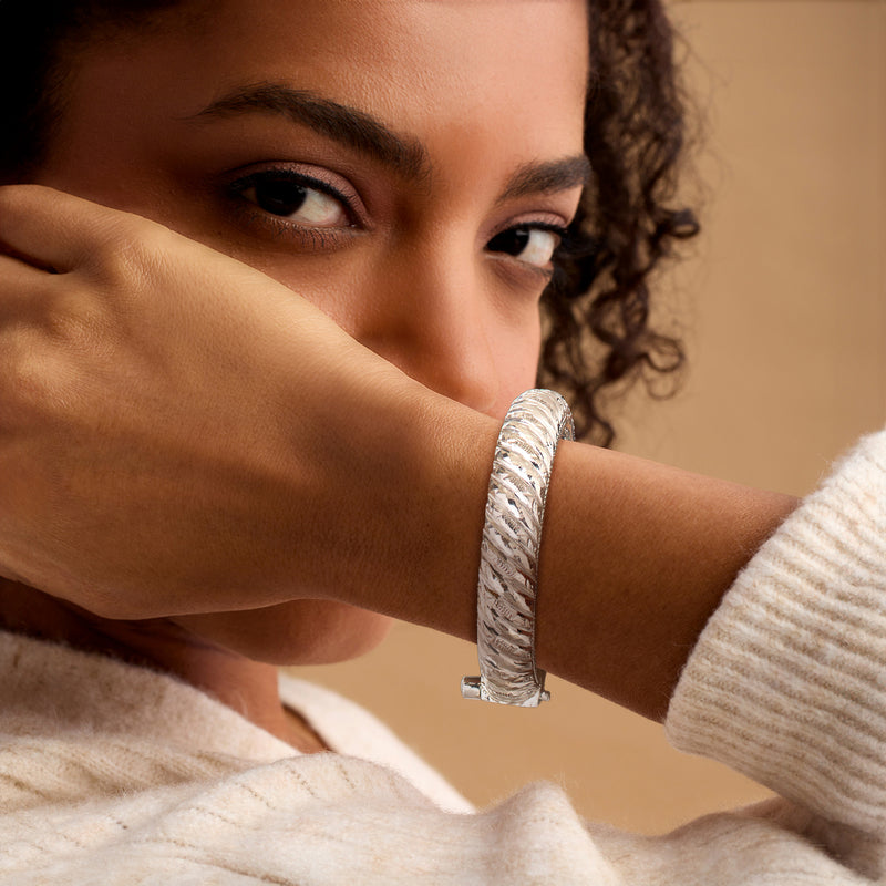 Sterling silver etched bangle bracelet worn on wrist, ribbed texture