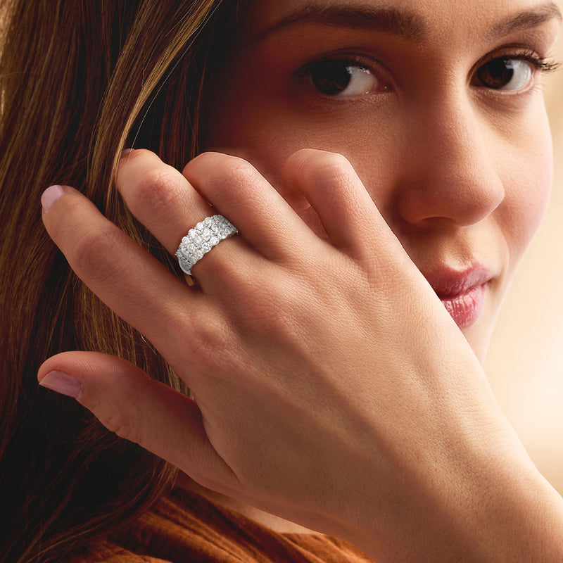 Platinum three-row diamond ring on finger with prong-set round stones
