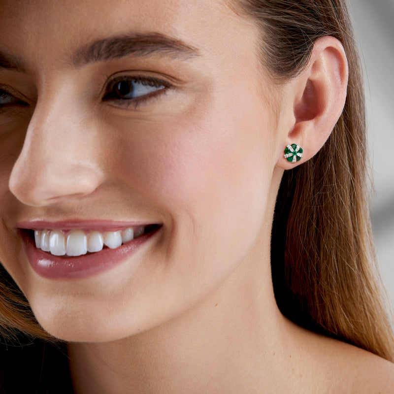 Emerald and diamond flower stud earrings on ear, green center with white stones