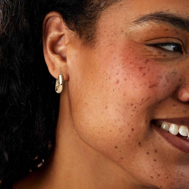 Squared yellow gold hoop earrings on ear, polished 14kt finish
