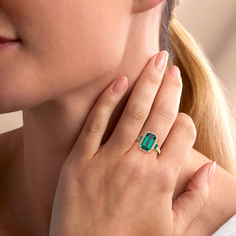 Emerald-cut emerald ring in 10kt yellow gold with white stones, on finger