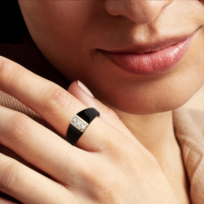 Square diamond and black onyx ring on finger in yellow gold bezel setting