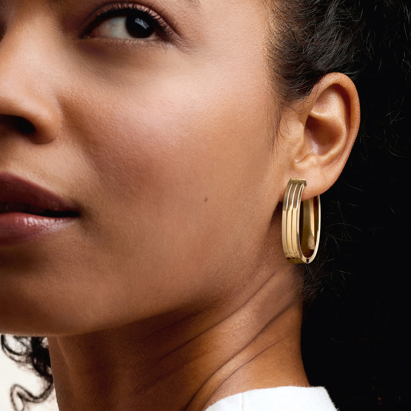 Oval hoop earrings in 14kt yellow gold on model's ear