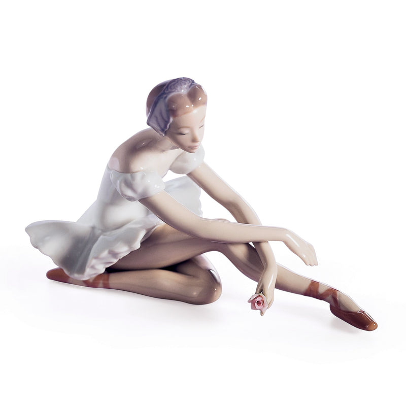 Seated porcelain ballerina figurine in white dress with pink rose detail