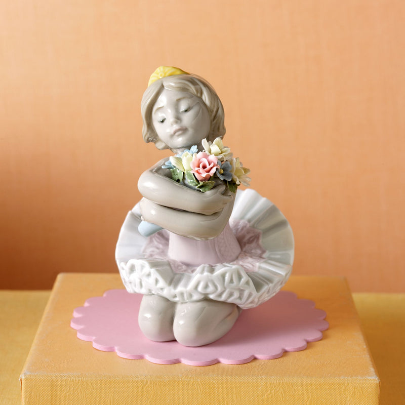 Lladro porcelain figurine of a ballerina kneeling, holding a flower bouquet, on a pink base