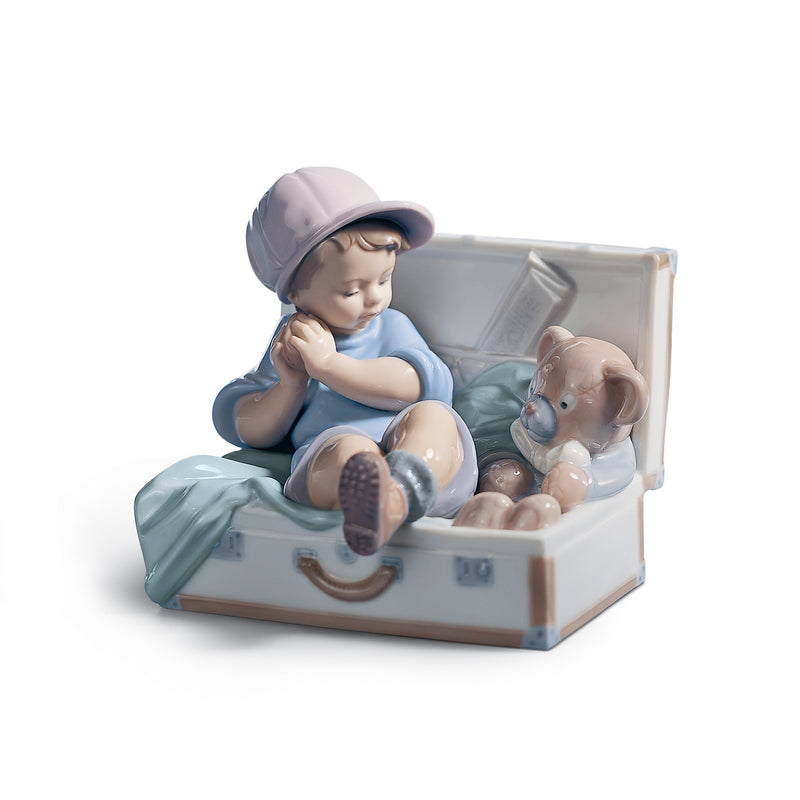 Porcelain figurine of baby in blue cap sitting beside another baby in open box