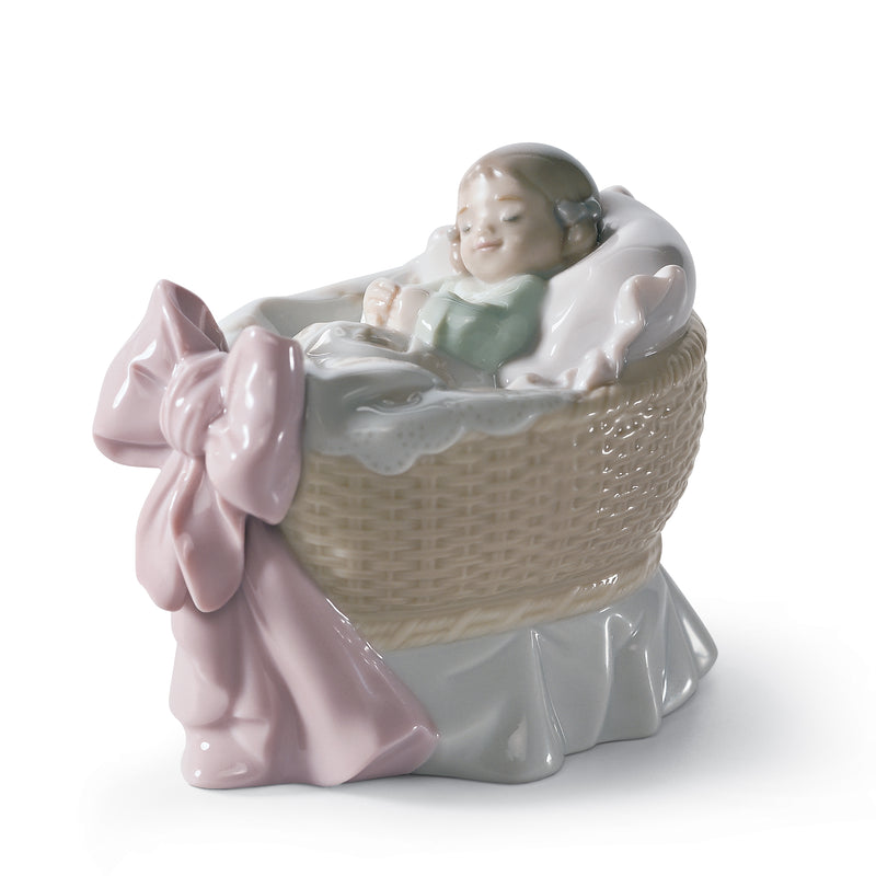 Lladro porcelain figurine of a seated child in a wicker basket holding a pink bow