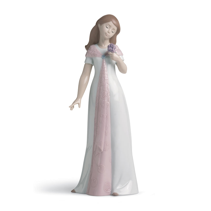 Porcelain figurine of a woman in a white and blush gown holding a small purple bouquet