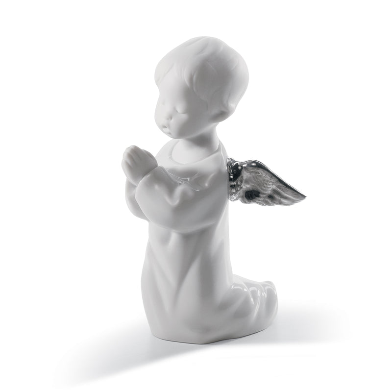 White porcelain angel figurine praying, holding a small dark bird with wings