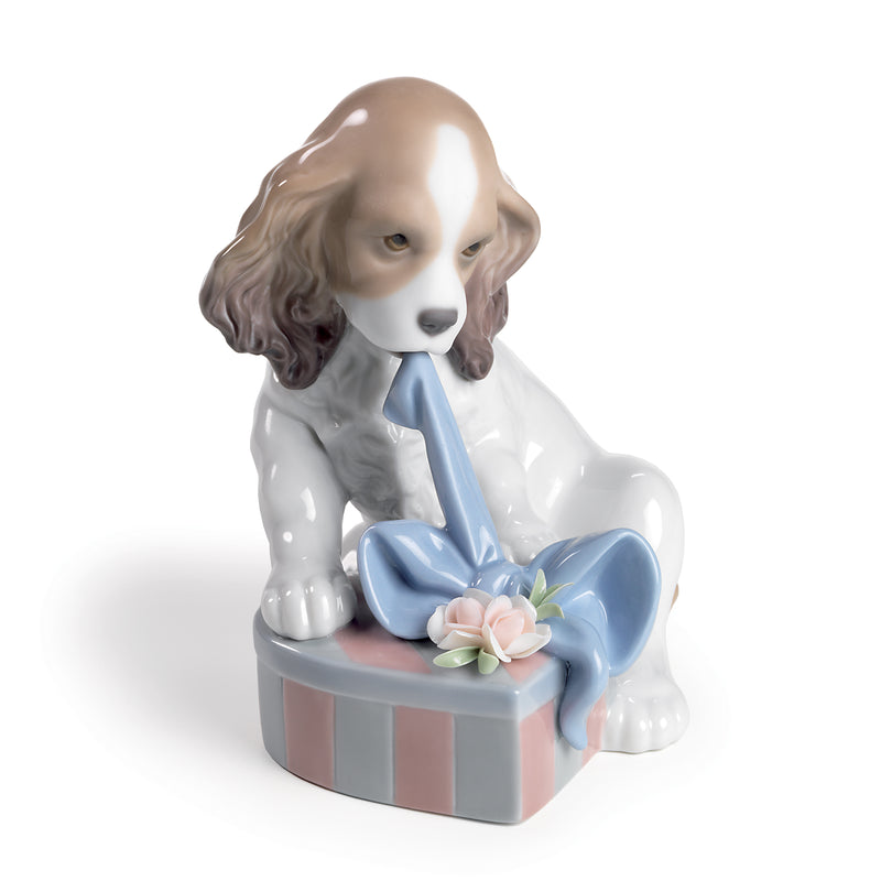 Porcelain figurine of a seated dog with a blue bow on a gift box