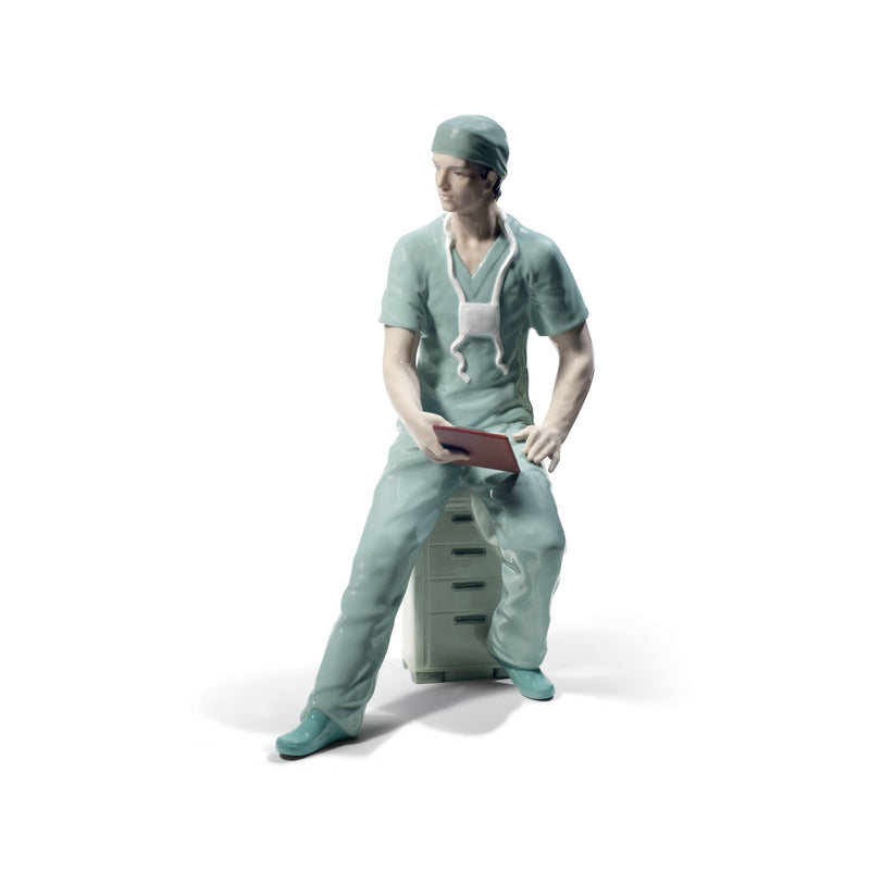 Lladro porcelain surgeon figurine in teal scrubs and cap, kneeling, holding a red clipboard